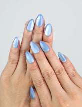 Hand wearing Naillover’s Frosted Skyline icy blue press on nails with soft cat eye shimmer.